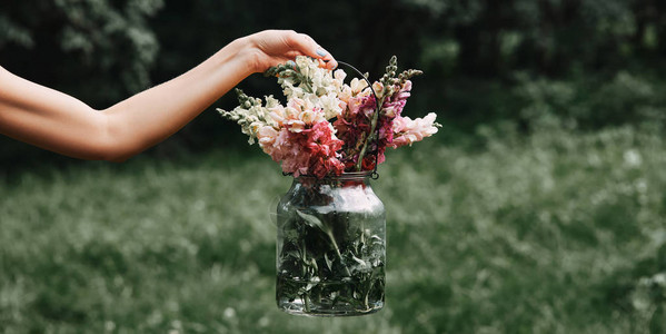 女用各种花朵盛着玻璃罐图片