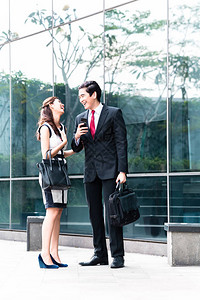 亚洲商人男女在大楼前用手机电话通图片