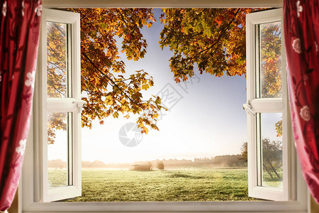 红窗帘打开时显示农村一栋房屋的现代窗口背景图片