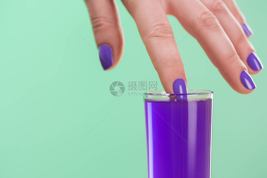 女用紫色鸡尾酒浸泡手指的作物形象在松图片