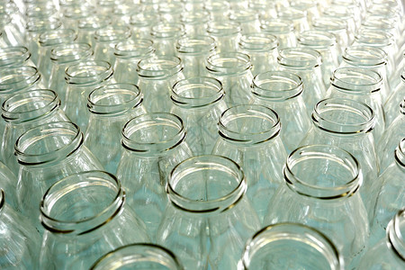 在装瓶厂工厂的生产线上或在商店出售的多排没有盖的透明空玻璃瓶背景图片