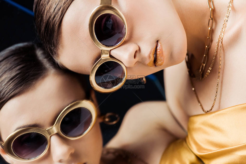戴墨镜的年轻女子躺在镜子上的金项链图片