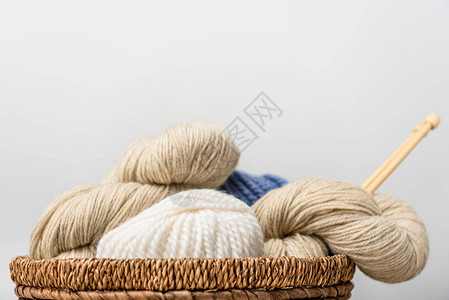 灰色背景下柳条篮中织针编织的近景图片