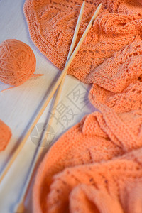 白色木质背景上的亮橙色格子针织针织和纱球图片