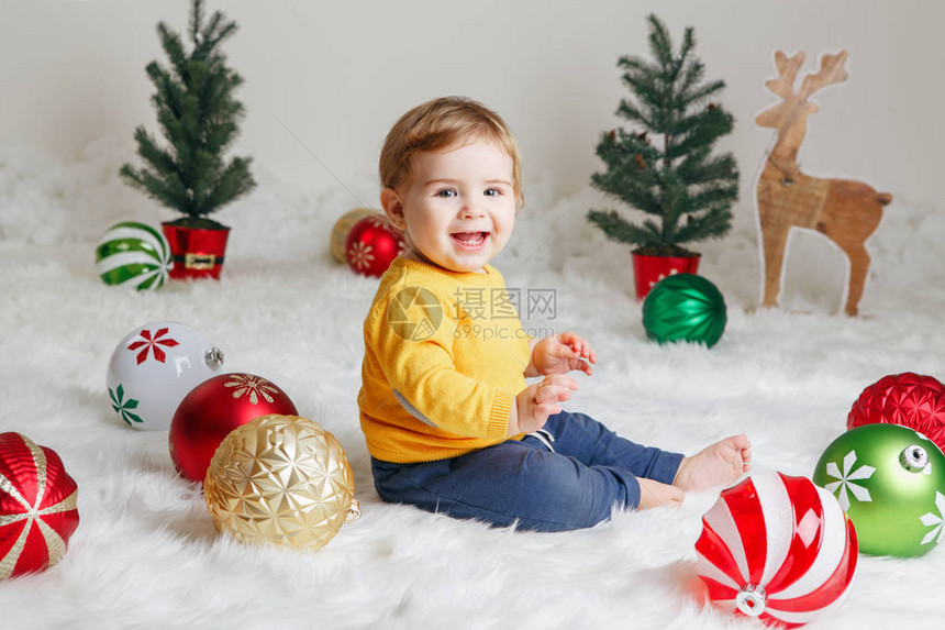 穿着黄色毛衣的高加索婴儿坐在白色蓬松的地毯上庆祝圣诞节或的肖像图片