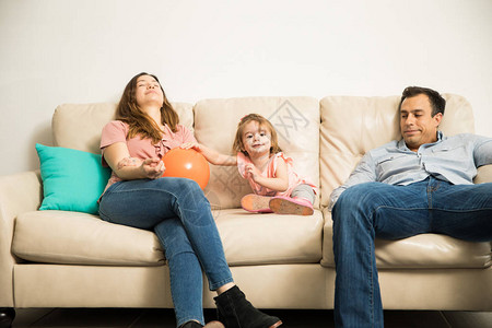 年轻西班牙裔父母在客厅沙发上用橙色球图片