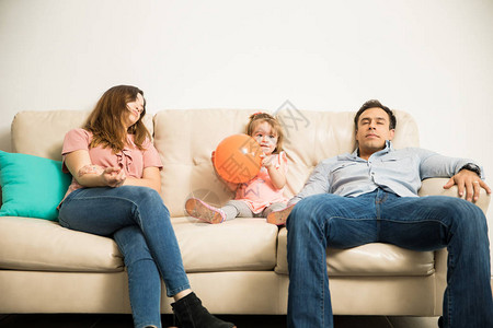 年轻西班牙裔父母在沙发上用橙色球图片