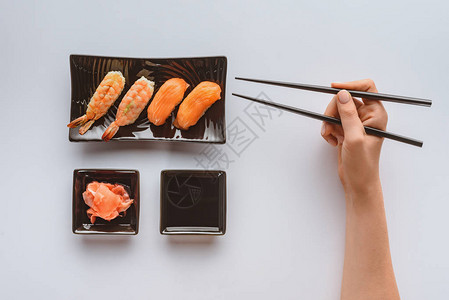 一个人拿着筷子和吃着美味的寿司在图片
