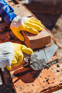 工匠在防护手套中被用垃圾填充器铺砖头的建筑图片