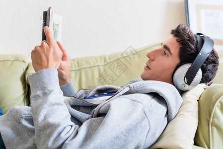 放松的年轻人躺在沙发上一边听音乐图片