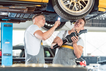 两名熟练的汽车机械技工在现代汽车修理厂工作时图片