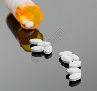 多片白色药物或维生素片剂从药瓶或容器溢出到反图片
