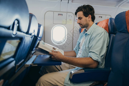 一名年轻男子在飞行时坐在飞机座椅上木板高清图片素材