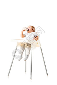 可爱的小孩男喝着婴儿瓶酒坐在高椅子图片