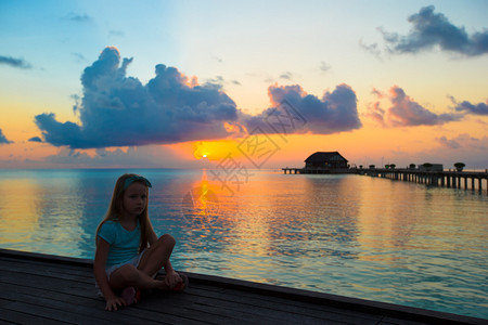 日落海滩上可爱小女孩的剪影图片