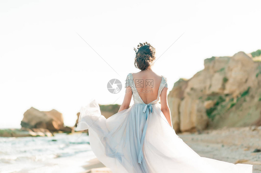 美丽的新娘穿着豪华婚纱与海边的花束海边的婚礼新娘在海中走来去图片