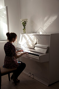 弹白色钢琴与窗外的光相对的女背景图片
