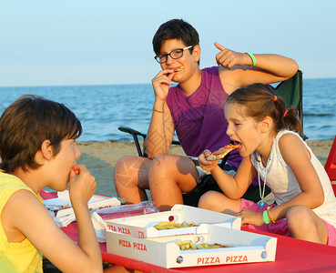 快乐的三兄弟在沙滩上吃披萨图片