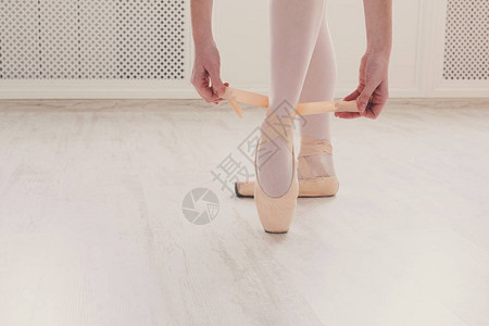 年轻芭蕾舞女演员美丽纤细的双腿在白色木地板背景上穿足尖鞋图片