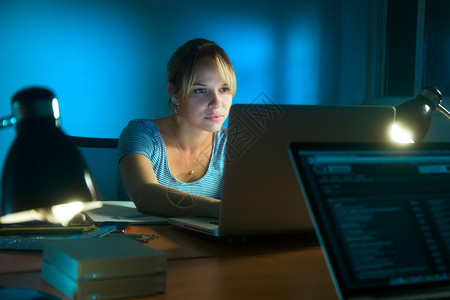 深夜在办公室工作用笔记本电脑在社交网络上网和写文章的漂亮女图片