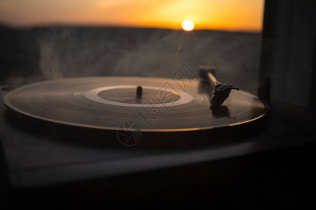 在山上日落的上的转盘黑胶唱片播放器DJ混合和播放音乐的声音技术胶唱片老式黑胶唱片播放器黑背景图片