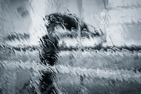 一个模糊不清的女人在雨下摇着脚影带着雨伞穿过潮湿的窗图片