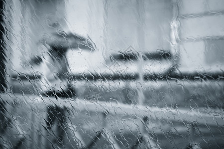 一个模糊不清的女人在雨下摇着脚影带着雨伞穿过潮湿的窗图片