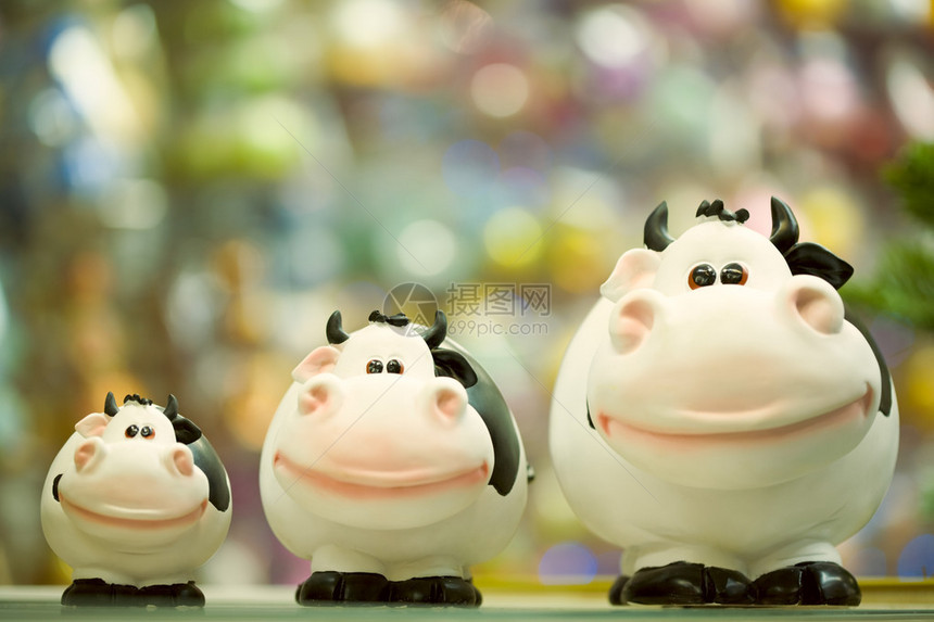 3头肥玩具奶牛站在商店窗户上排图片