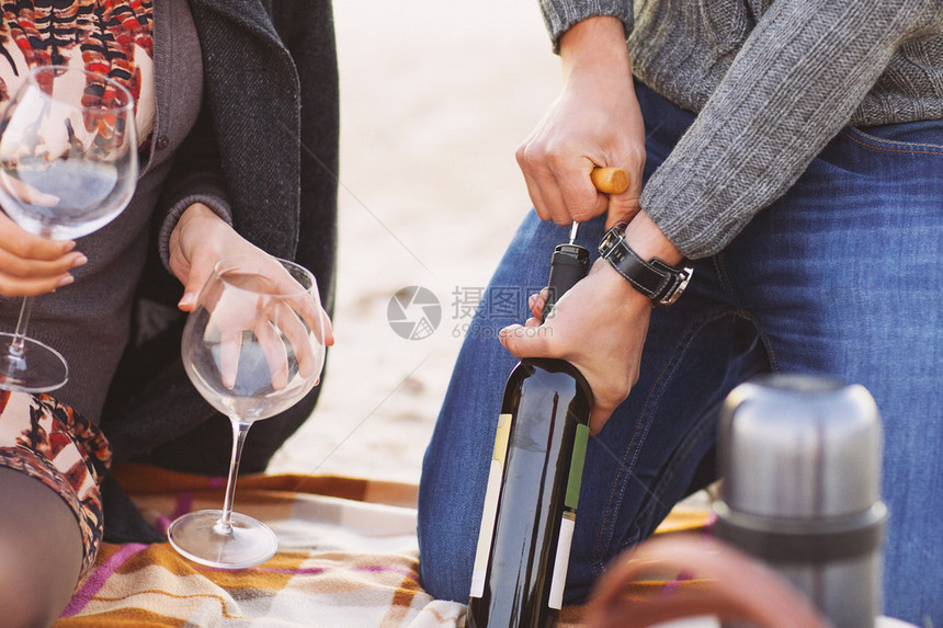 年轻快乐的情侣一起享受海滩野餐男人开酒图片