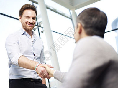 两位天主教商人通过在现代办公室握手互相打招呼背景图片