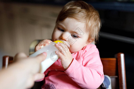 可爱的女婴喝配方奶妈拿着奶瓶为婴儿提供的第一餐新出生的孩子图片