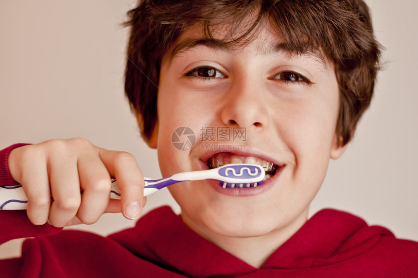 快乐的青少年与牙套和刷牙他的牙齿Ortod图片