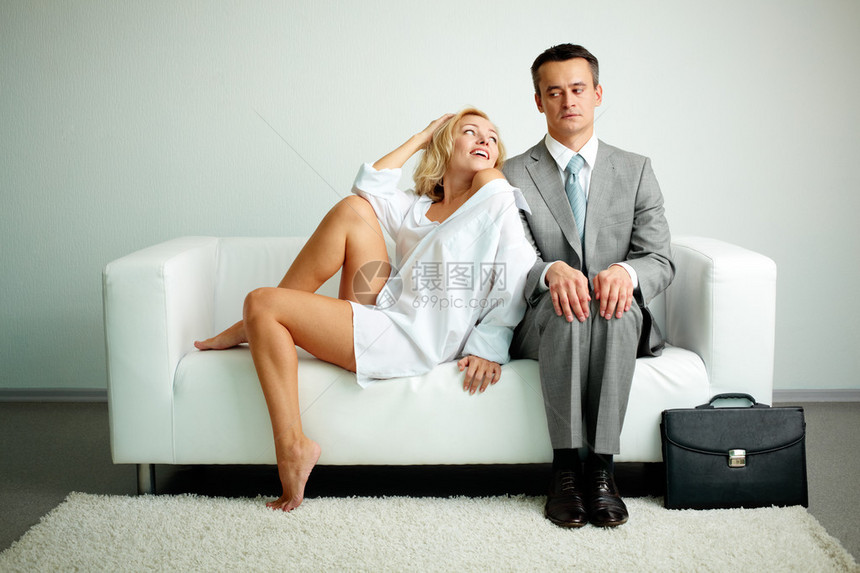 照片上严重男子坐在沙发上与有诱惑力的女图片