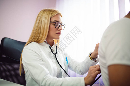 年轻的金发年轻医生正在医务室对病人进图片