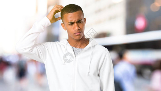 穿着白色运动衫的黑皮肤青年男子有疑惑和混淆脸部表情背景图片