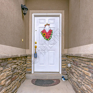 有白色前门的家狭窄的入口带有白色木质前门和门把手的住宅的狭窄入口一盏灯门饰和鸟雕像装饰着这背景图片