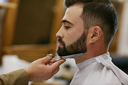 理发师在理发店为有黑头发和胡子的英俊图片