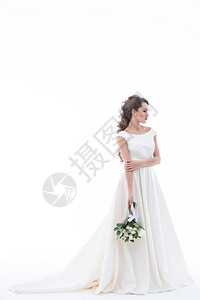 穿着传统白色礼服的优雅新娘带有婚礼花束图片