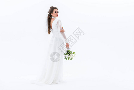 穿着传统婚纱的新娘手持婚礼花束在白图片