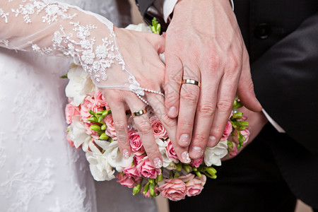 美丽的婚礼花束上的手和戒指图片