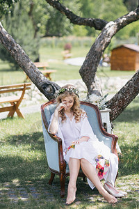 美丽的年轻赤脚新娘鲜花圈坐在扶手图片