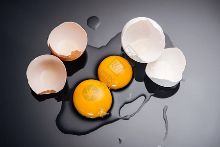 黑色背景中带有蛋黄蛋白质和蛋壳的生碎鸡蛋的顶部视图图片