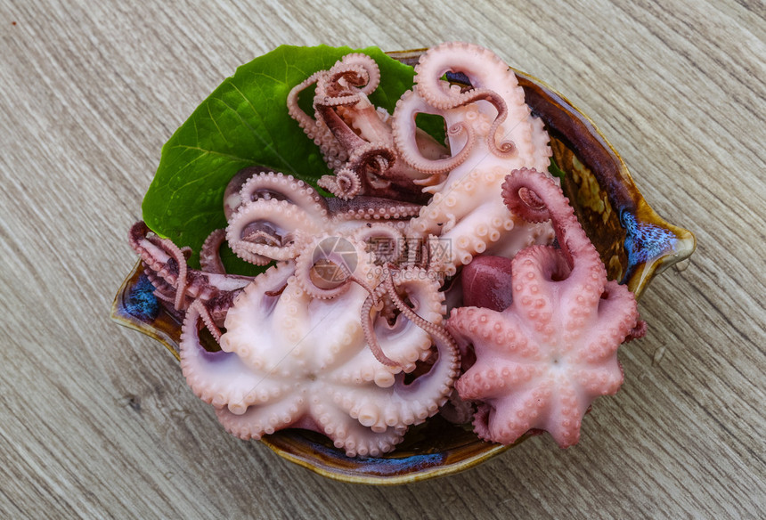 在木背景的碗里腌制的小章鱼图片