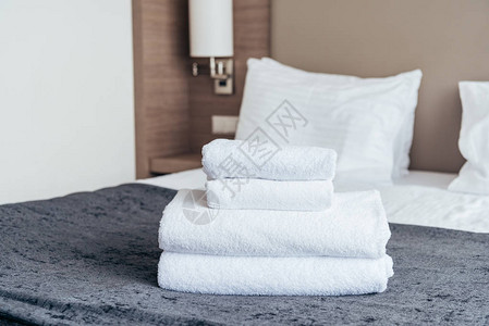 酒店房间床上折叠的白毛巾背景图片