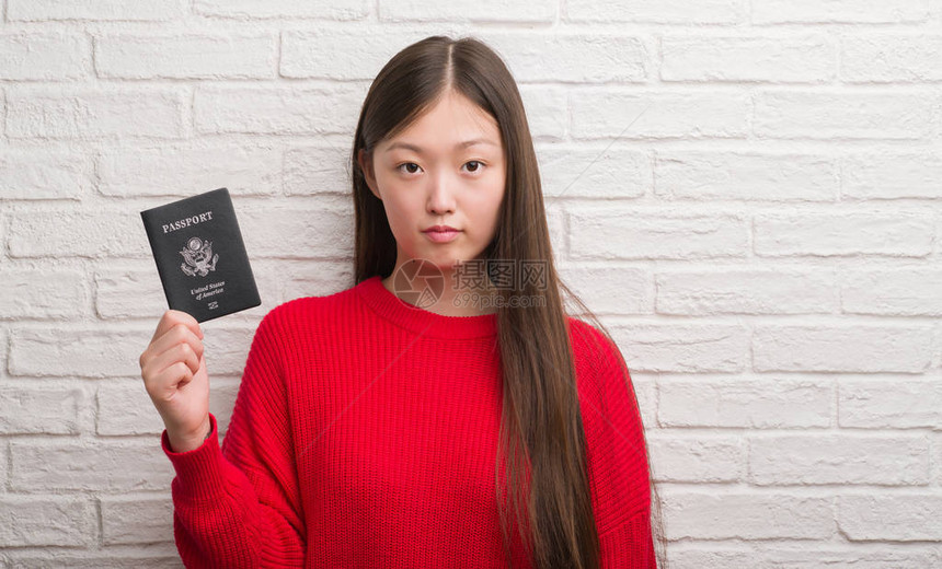 持有美国护照的年轻女子在砖墙上翻墙图片