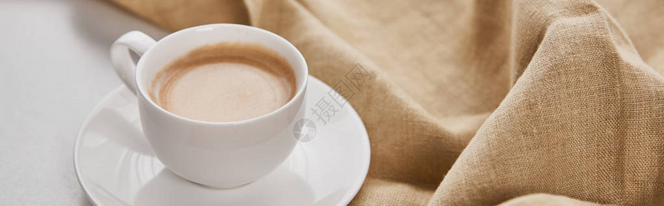 餐巾旁的茶碟上白色杯子咖啡中咖啡的近图片
