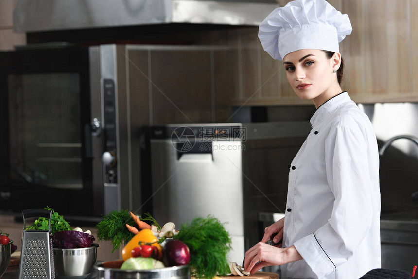 专业女厨师在餐饮厨房切菜料材的图片