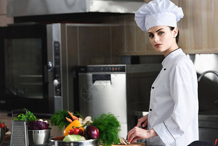 专业女厨师在餐饮厨房切菜料材的图片