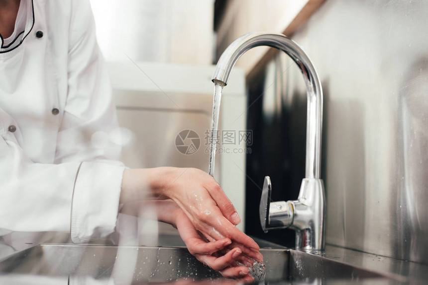 女厨师在厨房水槽上洗手的剪影图片