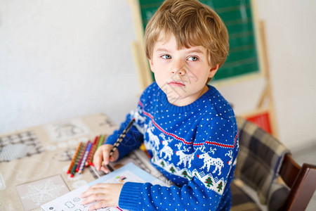 在家做作业的沮丧的伤心学校孩子男孩的画像小孩用彩色铅笔在室内写字图片